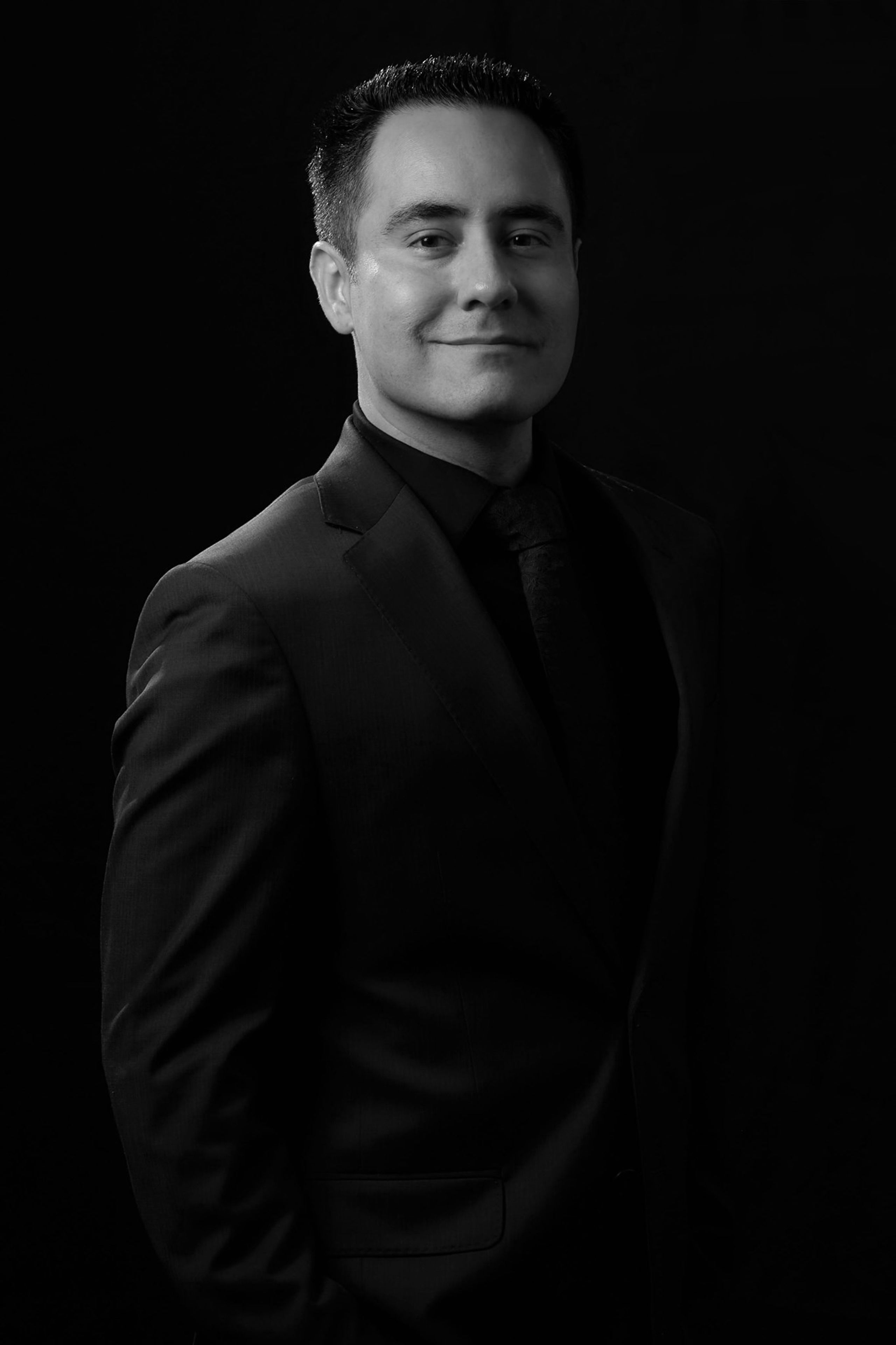 Professional black-and-white portrait of Richard Saenz of Royal Films in a suit against a dark background